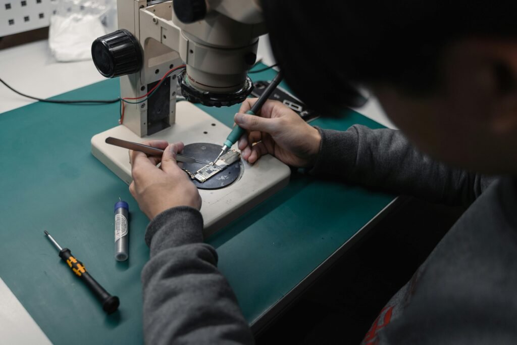 pexels-photo-6755066-6755066 Technician using a microscope to repair a broken electronic board with precision tools.